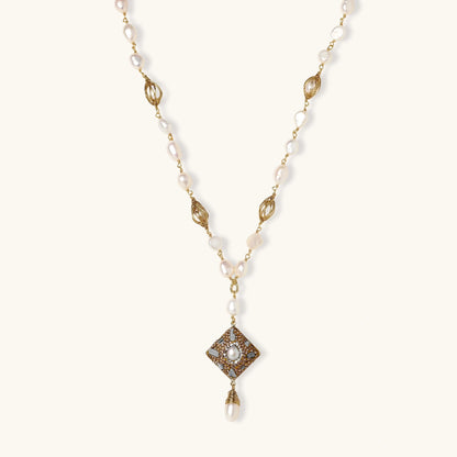 Y-shaped necklace with freshwater pearls, gold filigree stations, and ornate diamond-shaped centerpiece with pearl drop